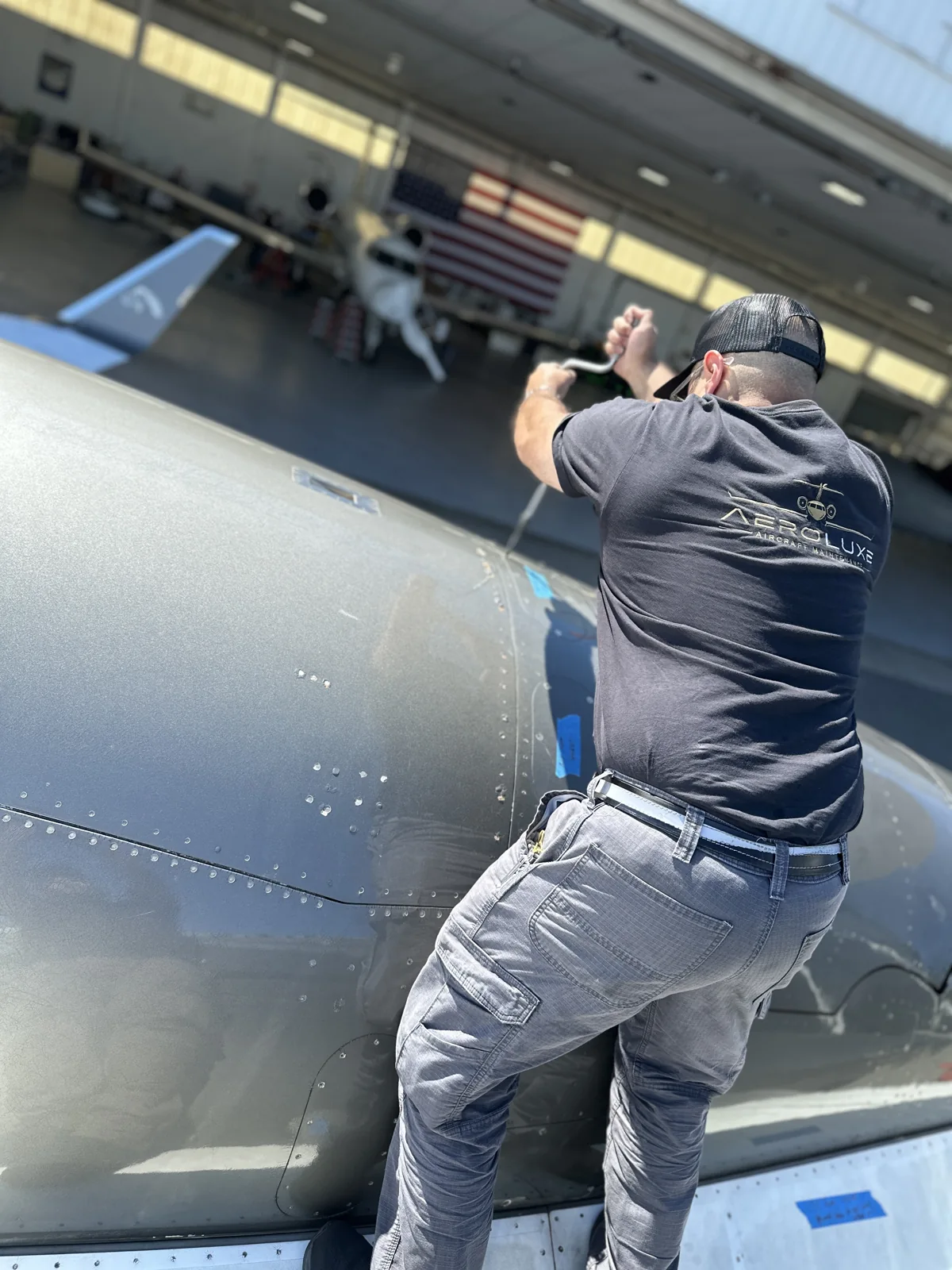 An Aeroluxe technician at work beside an aircraft nacelle.